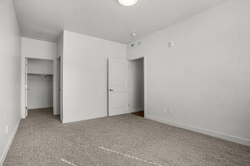 A room with a carpeted floor and two doors.