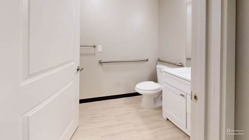 A white bathroom with a toilet, sink, and a towel bar.