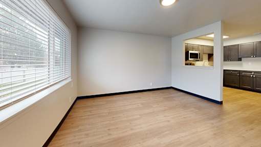 A room with wooden flooring and a window with blinds.