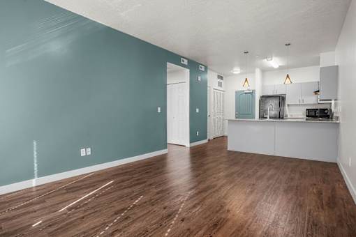 A room with wooden floors and a kitchen area.