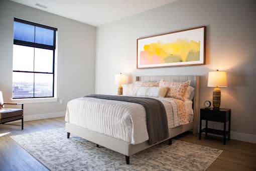 A bedroom with a large bed and a painting on the wall.