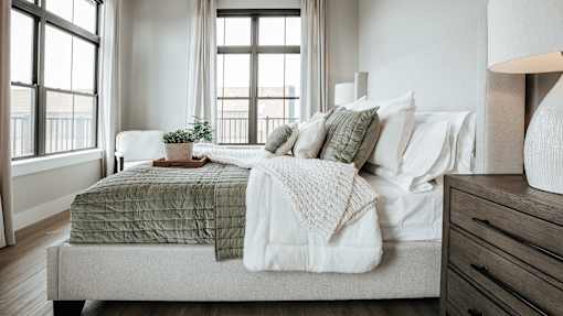 A bedroom with a bed covered in a green and white comforter.