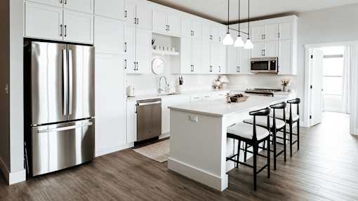 A modern kitchen with a white color scheme and stainless steel appliances.