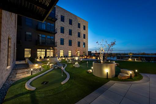A modern building with a well-lit outdoor area at dusk.