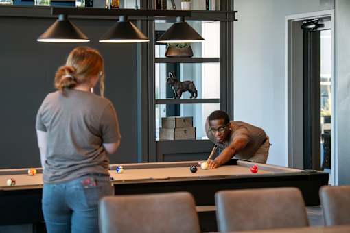 A man and a woman playing pool in a room.