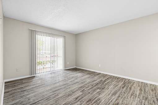 A room with wooden flooring and a sliding glass door.