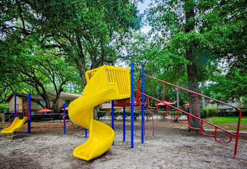 A playground with a yellow slide and red and blue swings.