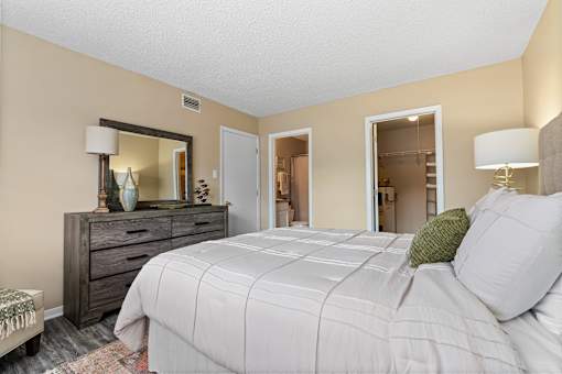 A bedroom with a large bed, a dresser, and a mirror.
