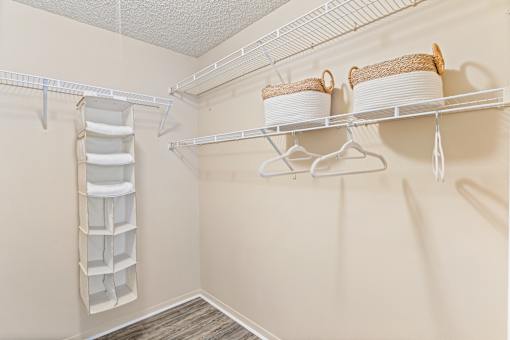 A white shelf with two baskets and a white container on it.