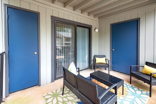 a patio with a table and chairs and two blue doors
