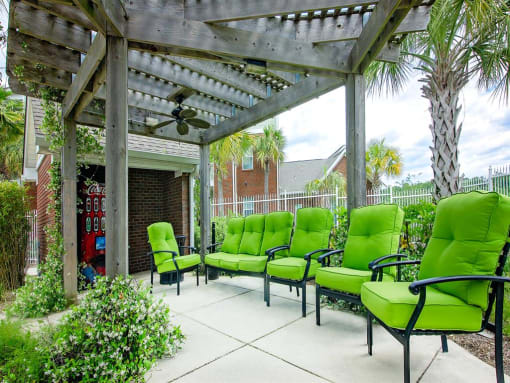 outdoor chairs with green cushions under a pavilion