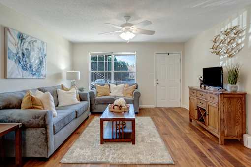 A living room with a grey couch, a wooden coffee table, and a wooden cabinet.