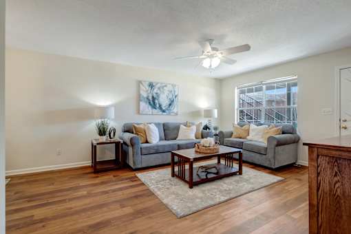 A living room with a grey couch, a coffee table, and a painting on the wall.