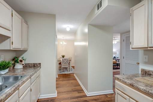 A kitchen with a dining area in the background.