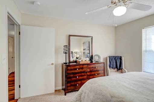 A bedroom with a bed, dresser, mirror, and a ceiling fan.