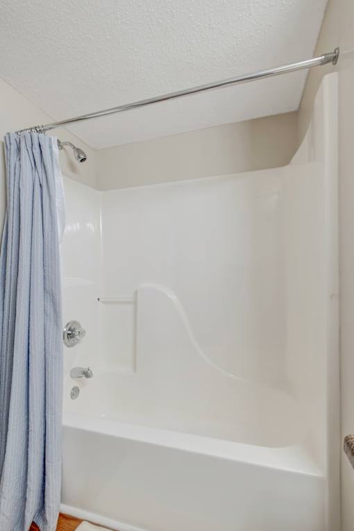 A white bathtub with a blue shower curtain.