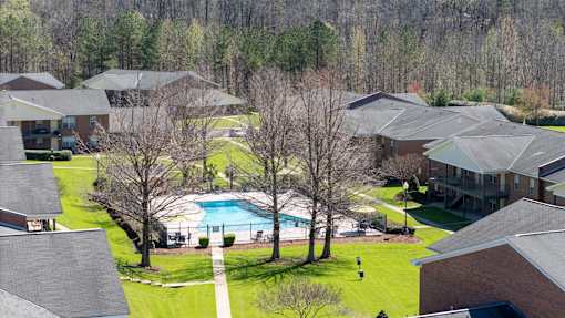 A swimming pool is surrounded by houses and trees.