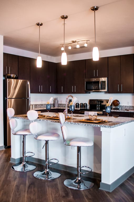 a kitchen with a bar and chairs and a stainless steel refrigerator