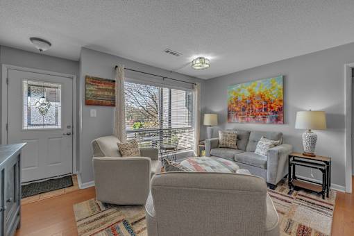 A living room with a grey couch and a painting on the wall.
