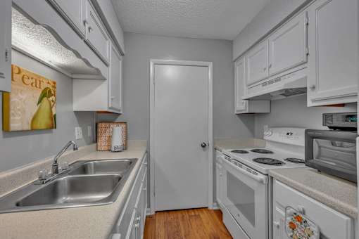 A kitchen with white cabinets and a white door.
