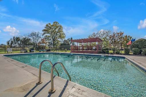 A swimming pool with a diving board and a building in the background.