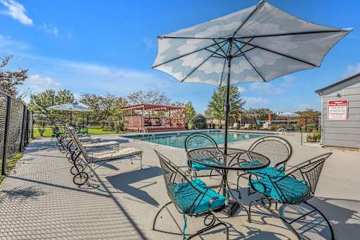 A patio with a table and chairs under an umbrella.