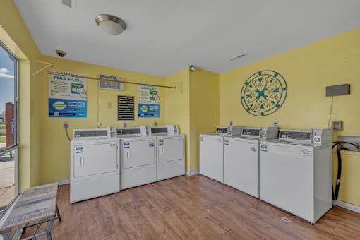 A yellow wall with a clock and washing machines.