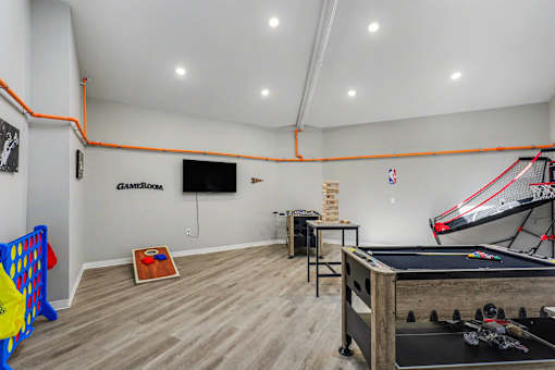 A room with a pool table, a basketball hoop, and a foosball table. at Mayfair Apartments, Kansas City, Missouri