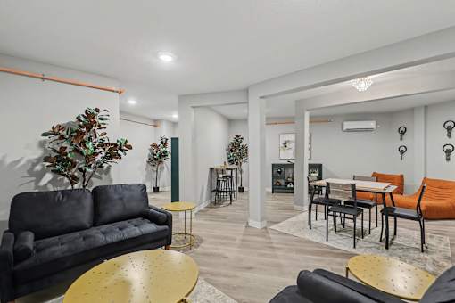 A living room with a black couch, a yellow table, and a green plant at Mayfair Apartments, Kansas City, 64145