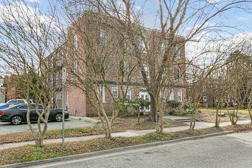 A large brick building with a tree in front of it at Shipyard Shores Apartments, Apartments, Newport News, VA