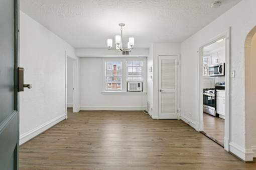A large empty room with a chandelier and a kitchen in the background. at Shipyard Shores Apartments, Newport News, 23607