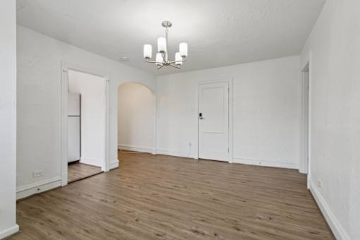 A room with a chandelier and wooden floors. at Shipyard Shores Apartments, Newport News, Virginia