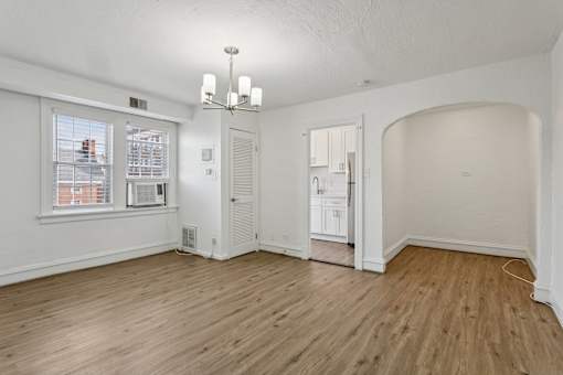 A room with a window, a chandelier, and a wooden floor. at Shipyard Shores Apartments, Newport News