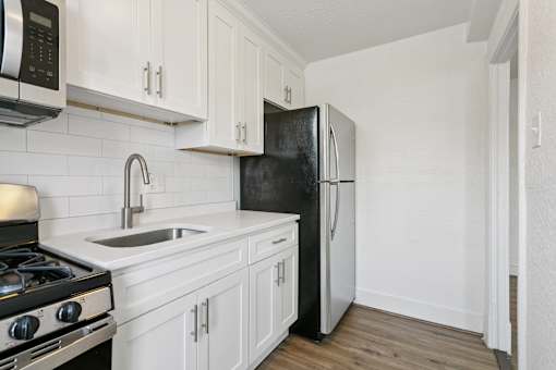 A black refrigerator is in a kitchen with white cabinets at Shipyard Shores Apartments, Newport News, VA, 23607