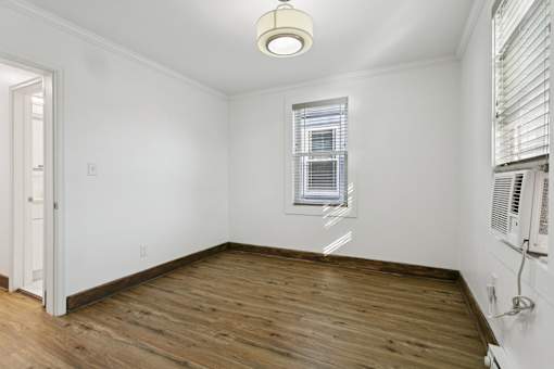 A room with wooden floors and a window with blinds at Shipyard Shores Apartments, Newport News