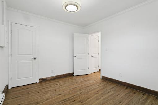A room with two white doors and a wooden floor at Shipyard Shores Apartments, Virginia