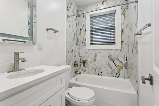 A white bathroom with a marble tile wall at Shipyard Shores Apartments, Virginia, 23607