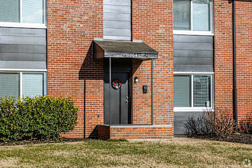 A red brick building with a black door and a small porch. at Blacklark Apartments, Apartments, Kansas City, KS