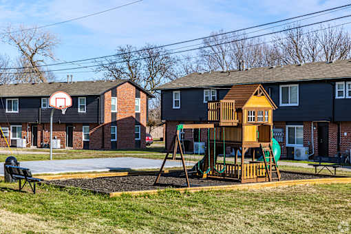 A playground with a basketball hoop and a wooden swing set. at Blacklark Apartments, Kansas City, KS, 66101