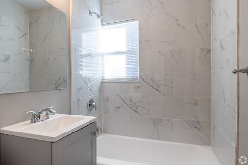 A bathroom with a marble wall and a white sink. at Blacklark Apartments, Kansas, 66101