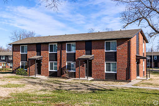 A red brick building with a brown roof and a white door. at Blacklark Apartments, Kansas, 66101
