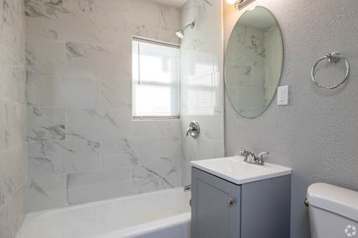 A bathroom with a marble wall and a round mirror. at Blacklark Apartments, Kansas City, KS, 66101