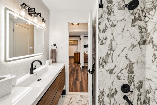 A bathroom with a marble tile shower and a wooden vanity.