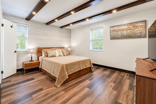 A bedroom with a large bed and wooden floors.