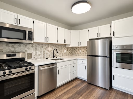 A modern kitchen with white cabinets and stainless steel appliances.