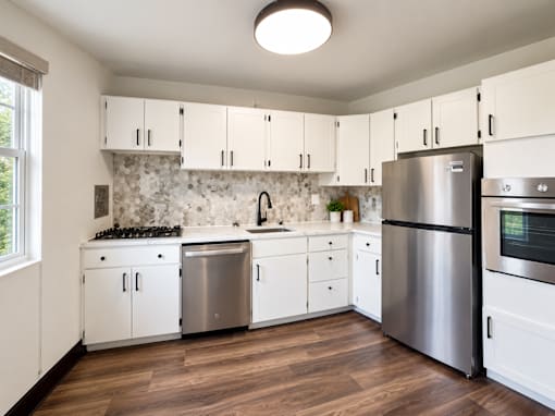 A kitchen with white cabinets and a stainless steel refrigerator.
