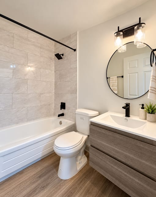 Modern bathroom with wood grain vanity at The Wyman Hills AHR LLC Apartments, Baltimore, MD