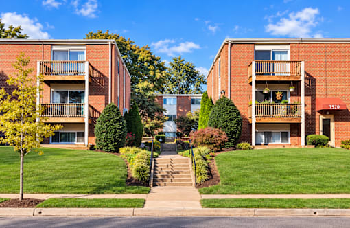 Brick apartment buildings with balconies and landscaped courtyard at The Wyman Hills AHR LLC Apartments, Baltimore, 21211