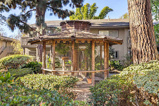 A wooden bird aviary is surrounded by green bushes at The Aspens Fairhaven, Santa Ana, 92705