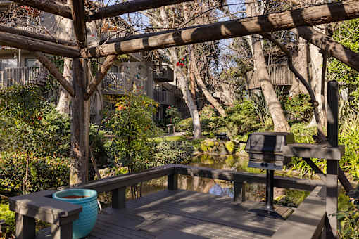 A wooden deck with a barbeque overlooking a lake at The Aspens South Coast, California, 92504